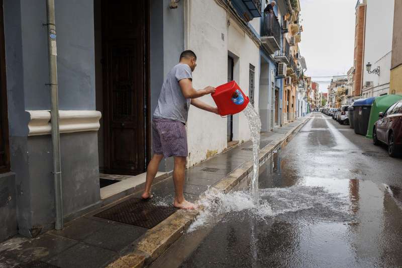 Un hombre achica agua de un local comercial de València tras las fuertes lluvias. EFE/Biel Aliño/Archivo

