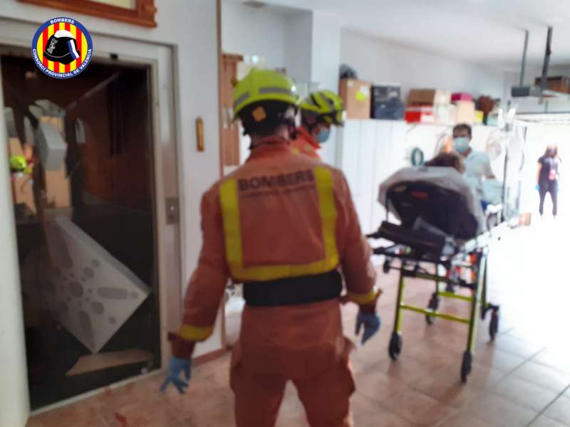 Bomberos asistiendo a dos mujeres tras desplomarse el ascensor de una vivienda en Benirredrà. EPDA