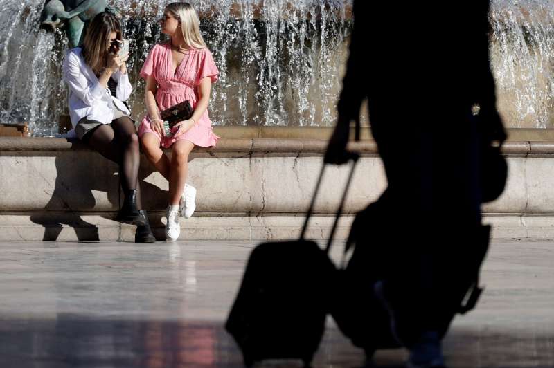 Unas turistas consultan el móvil y otro arrastra unas maletas, en una imagen reciente de València. EFE/Kai Försterling