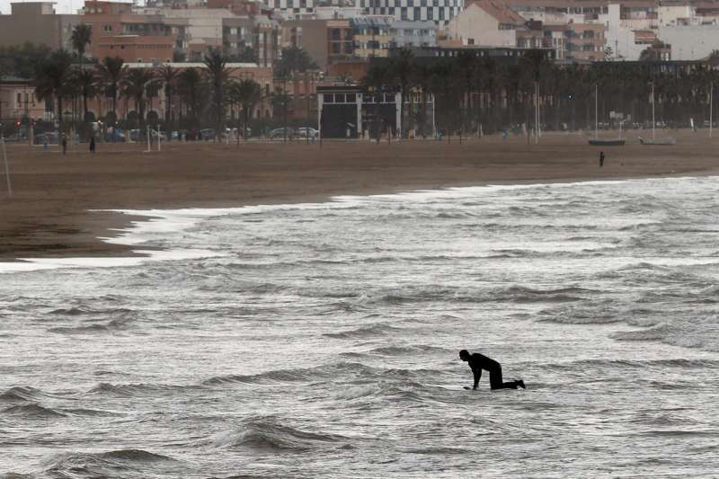 Una persona practica surf en la playa de la Malvarosa. EFE