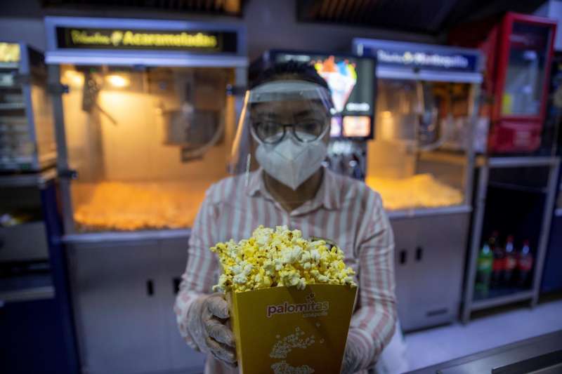 Una mujer ofrece palomitas en una sala de cine. 
