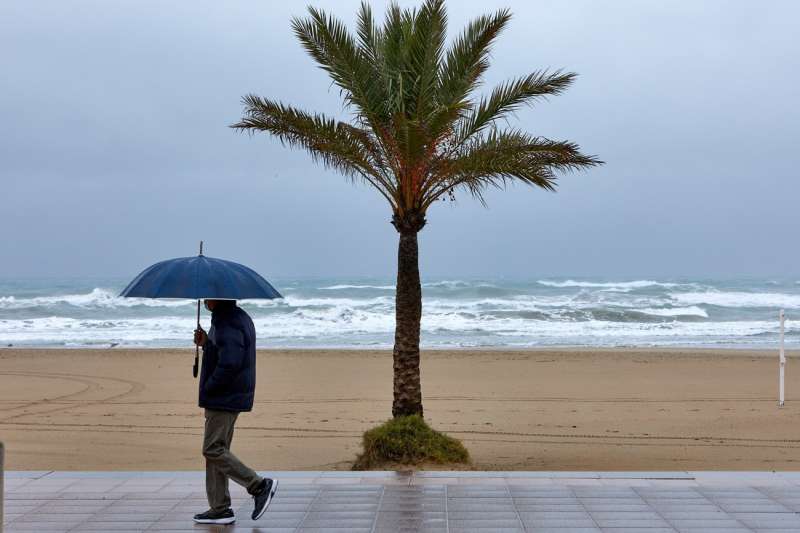 Una persona se protege de la lluvia en el paseo martimo de Ganda. EFENatxo Francs
