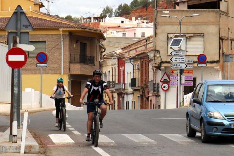 Dos ciclistas y un vehculo circulan por la CV-377 en Pedralba. JUDITH CELMA
