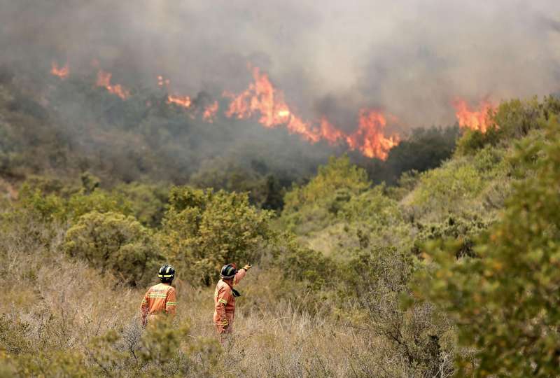 Dos bomberos observan las llamas provocadas por un incendio. EFEManuel BruqueArchivo
