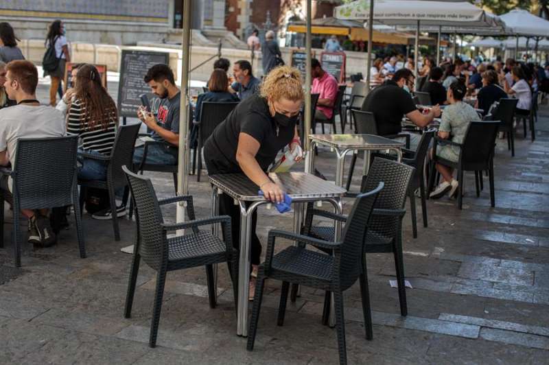 Una camarera desinfecta una mesa de una terraza en el centro de València. EFE