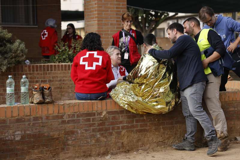 Miembros de la Cruz Roja asisten a una persona en el exterior del colegio Llus Vives de Massanassa (Valencia).  EFE