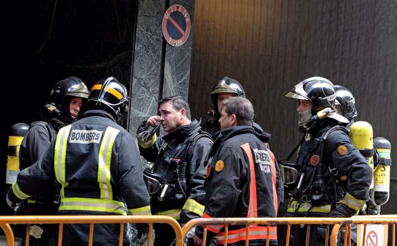 Varios bomberos protegidos con máscaras de oxígeno por la humareda generada por un incendio. EFE/Manuel Bruque/Archivo
